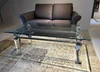Eleganter Couchtisch aus Acryl und Glas von Kuatre, Ausstellungsstück auf Designteppich vor Frontansicht des Schröno Sofa Individual in braunviolettem JAB Anstoetz Stoff Vito 55