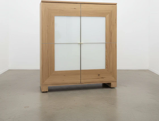 Großer Schrank Modell Varus von Scholtissek, Frontansicht in knorriger Eiche puro geölt mit Glaseinsatz in weiß satiniertem Optiwhite – Sonderangebot als.