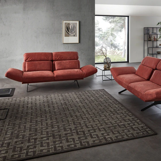 Seitenansicht des Relaxsofas Meda mit verstellbarer Rückenlehne in tiefrotem Leder – stilvolle Kombination aus Gemütlichkeit und geometrischer Eleganz.