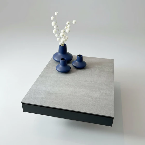 Funktionaler Couchtisch JANUS Janas mit ausgezogener Ablage und Edelstahlfuß – Designmöbel bei Zeppenfeld Wohn Evolution in Olpe.