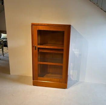 Form Exclusiv Vitrine „Premium“ 1-türig in Kirschbaum, Frontansicht im Raum, Ausstellungsstück mit Original-Transportleisten, feine Messingbeschläge,.