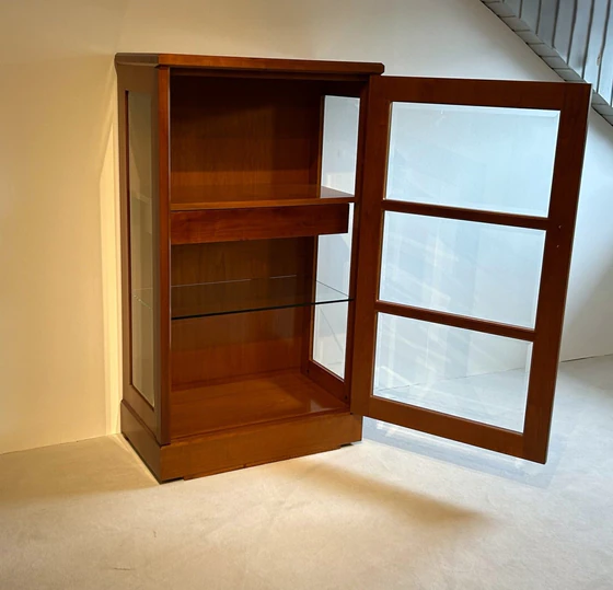 Form Exclusiv Vitrine geöffnet: Innenansicht mit Glaseinlegeboden und Schublade, Kirschbaumholz warmtonig, Facettverglasung sichtbar, Ausstellungsstück mit nur leichten Lagerspuren.