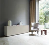 Wohnsituation mit Nex Pur Box Sideboard in komplettem Seidengrau: links Türmodul 1536778, rechts Schubkastenelement 1536776, vor grauer Wand mit großer Fensterfläche und Designstuhl.