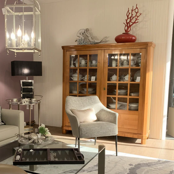 Form Exclusiv Camargue – Landhausvitrine in Kirschbaum massiv, 155×162×46 cm, Ambienteansicht mit Sessel