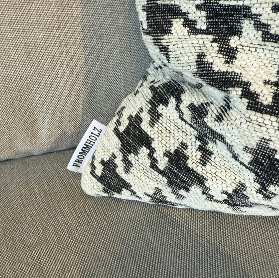 Nahaufnahme des Hahnentritt-Kissens mit Frommholz-Label auf dem grauen Sofa