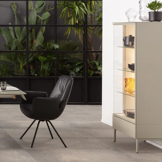 AERA Stuhl Gavi Lody mit Armlehne, Leder Dino schwarz, drehbares Rundrohrgestell schwarz, neben Sudbrock Vitrine Cubo