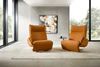 Zwei Relaxsessel Nolte Lounger Miami in orangefarbenem Nappaleder in modernem, lichtdurchflutetem Wohnraum mit Betonwand und abstraktem Kunstbild.