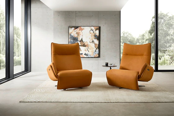 Zwei Relaxsessel Nolte Lounger Miami in orangefarbenem Nappaleder in modernem, lichtdurchflutetem Wohnraum mit Betonwand und abstraktem Kunstbild.