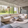 Sofa Nimbo von Bielefelder Werkstätten in einem hellen eleganten Wohnraum mit Sprossenfenstern, skulpturaler Stehleuchte und spiegelnden runden Couchtischen.