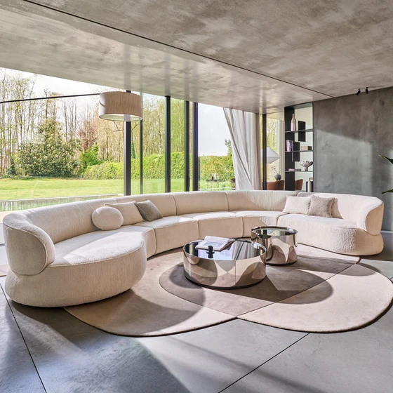 Sofa Nimbo von Bielefelder Werkstätten in einem hellen eleganten Wohnraum mit Sprossenfenstern, skulpturaler Stehleuchte und spiegelnden runden Couchtischen.