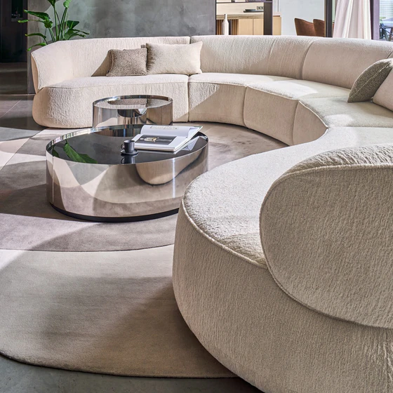 Detailansicht des Bielefelder Werkstätten Sofa Nimbo von oben mit großzügiger geschwungener Sitzfläche, weich gerundeter Armlehne und cremeweißem Strukturstoff.