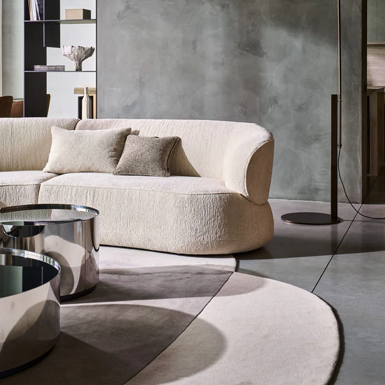 Detailaufnahme des Sofa Nimbo von Bielefelder Werkstätten mit rundem Abschlusselement, cremeweißem Strukturstoff im eleganten Wohnambiente.