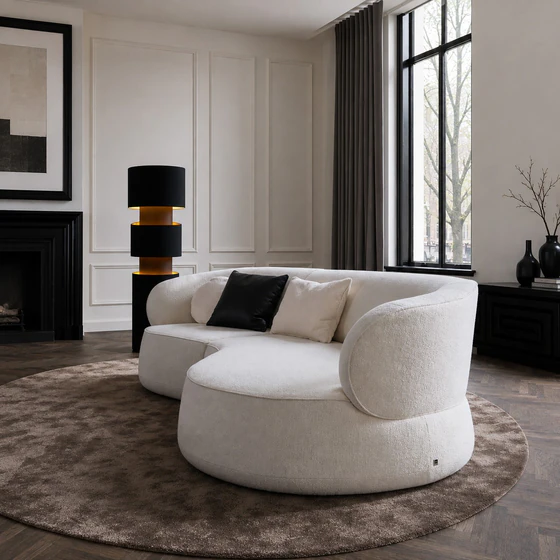 Detailaufnahme des Sofa Nimbo von Bielefelder Werkstätten mit rundem Abschlusselement, cremeweißem Strukturstoff und schwarzer Stehleuchte im eleganten Wohnambiente.