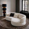 Bielefelder Werkstätten Sofa Nimbo in cremeweißem Strukturstoff in einem eleganten Wohnzimmer mit Sprossenfenstern, rundem Teppich und schwarzer Stehleuchte.